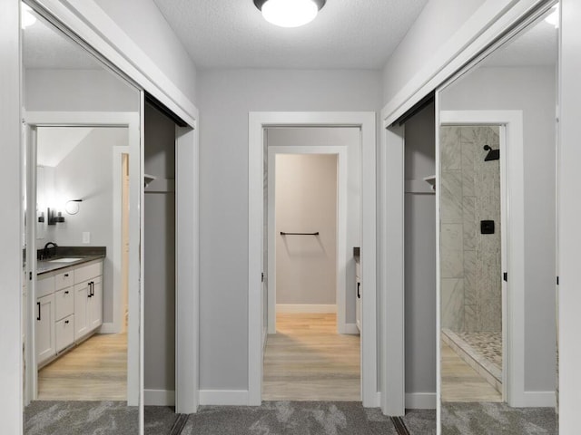 corridor featuring a textured ceiling and light carpet