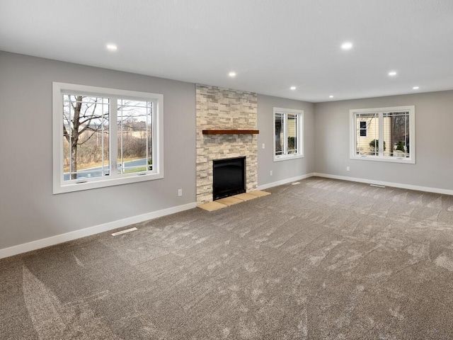 unfurnished living room with carpet flooring and a stone fireplace