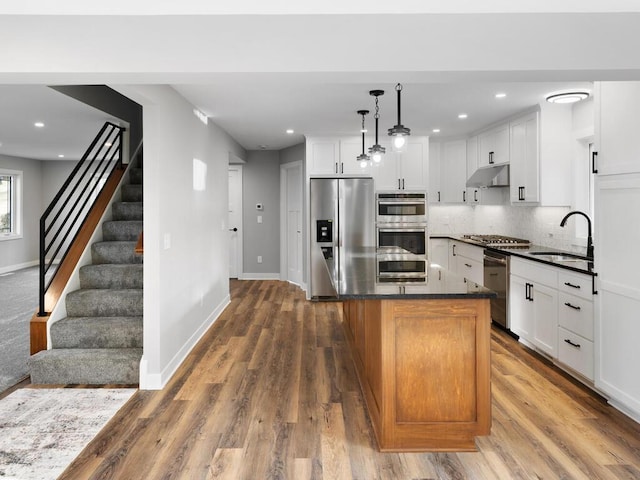 kitchen with pendant lighting, a center island, white cabinets, sink, and appliances with stainless steel finishes