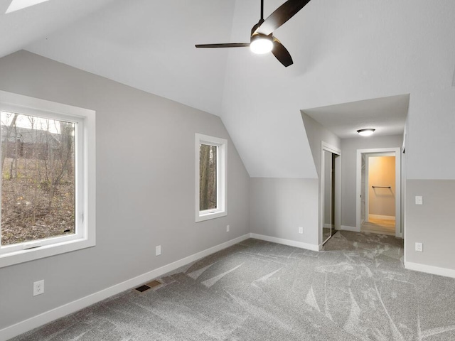 bonus room with light carpet, plenty of natural light, lofted ceiling, and ceiling fan