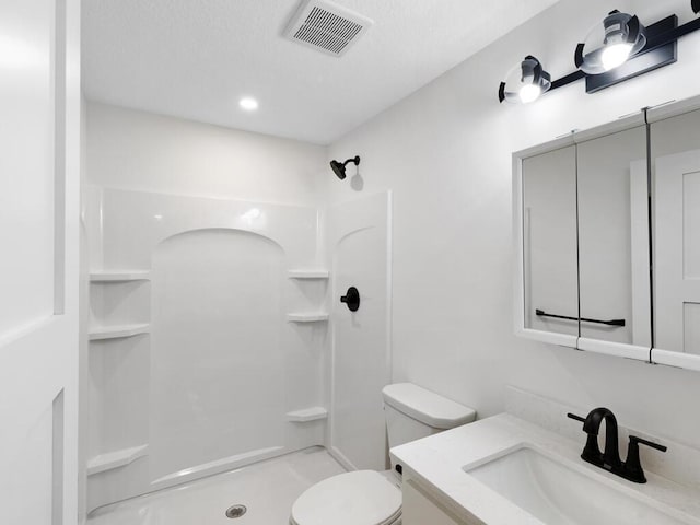 bathroom featuring vanity, toilet, and a shower