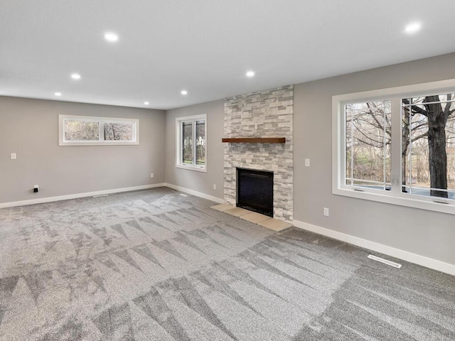 unfurnished living room featuring light carpet, a fireplace, and a healthy amount of sunlight