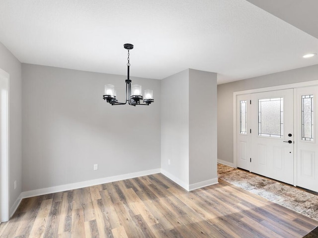 entryway with hardwood / wood-style floors and an inviting chandelier