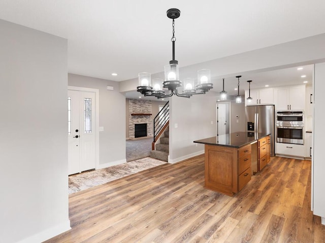 kitchen featuring a center island, white cabinets, hanging light fixtures, appliances with stainless steel finishes, and light hardwood / wood-style floors