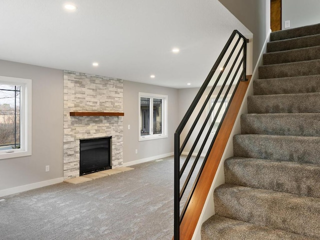 stairs with carpet flooring and a stone fireplace