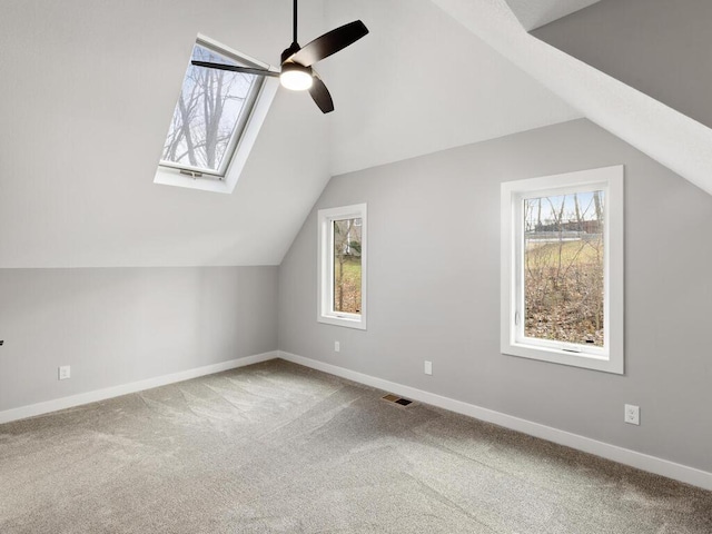 additional living space with carpet flooring, ceiling fan, and vaulted ceiling with skylight