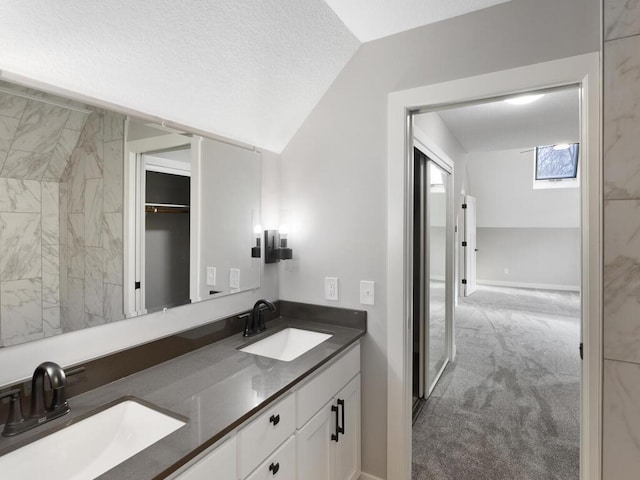 bathroom featuring a textured ceiling, vanity, and vaulted ceiling