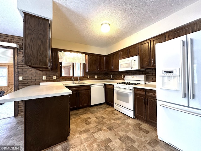 kitchen with kitchen peninsula, dark brown cabinetry, sink, and white appliances