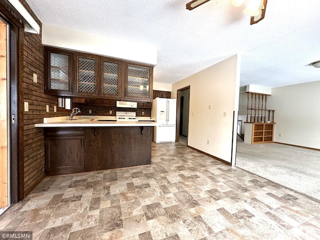 kitchen with white appliances, a kitchen breakfast bar, sink, a textured ceiling, and kitchen peninsula