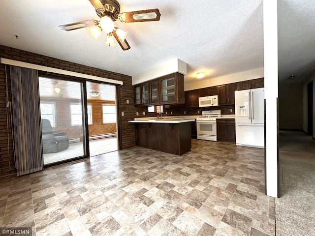 kitchen with white appliances, sink, kitchen peninsula, dark brown cabinetry, and brick wall