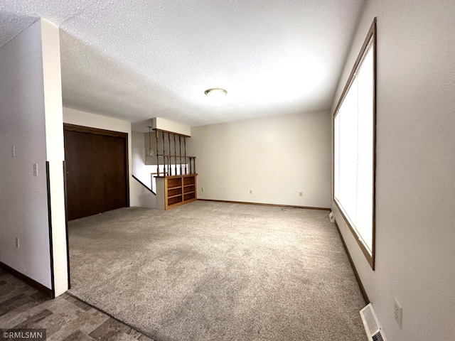 empty room featuring a textured ceiling and dark colored carpet