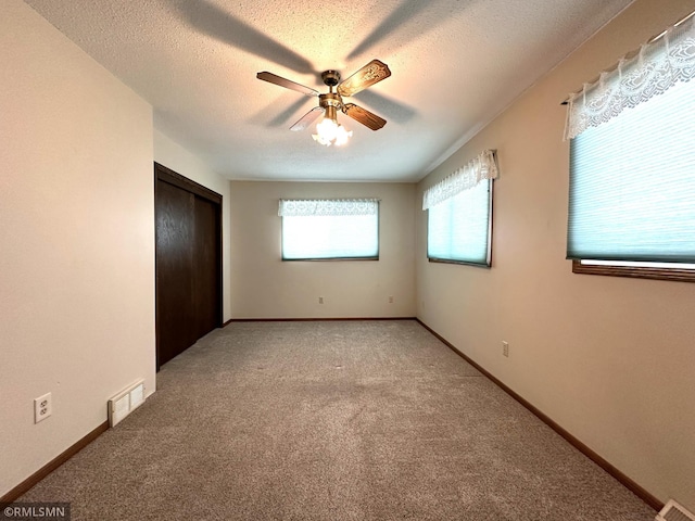 unfurnished bedroom with ceiling fan, carpet floors, a textured ceiling, and a closet