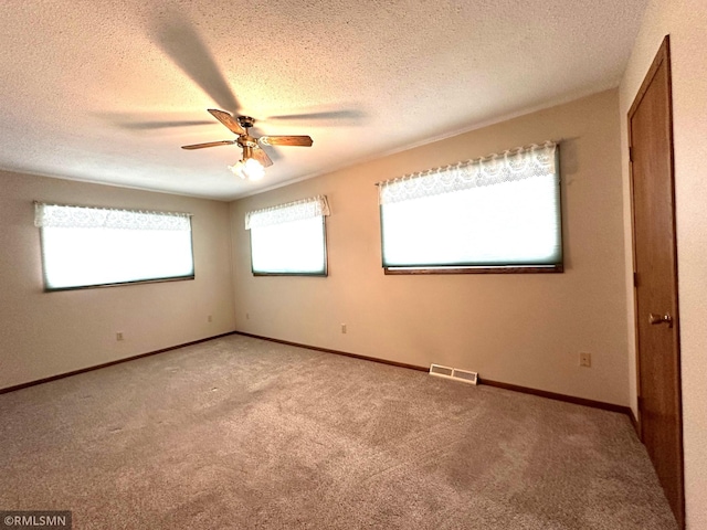 carpeted empty room featuring ceiling fan and a textured ceiling