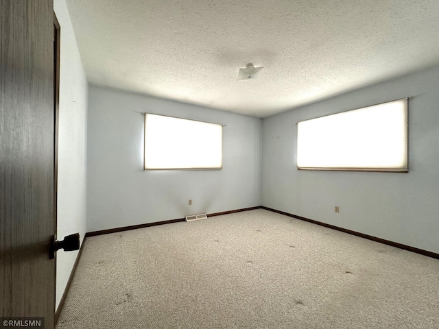 carpeted empty room with a textured ceiling