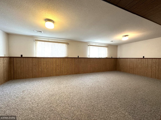 carpeted empty room featuring wood walls and a textured ceiling