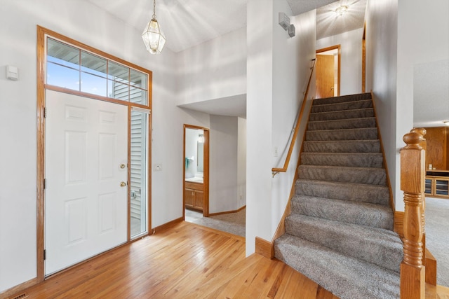 foyer featuring baseboards, stairway, and light wood-style floors