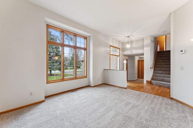 unfurnished living room featuring baseboards, carpet, stairs, and visible vents