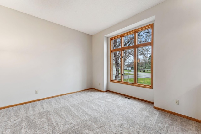 unfurnished room with baseboards, visible vents, and carpet