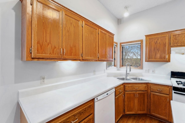 kitchen with white dishwasher, brown cabinetry, stove, and a sink