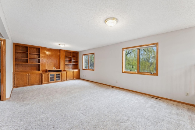 unfurnished living room with light carpet, a textured ceiling, and visible vents