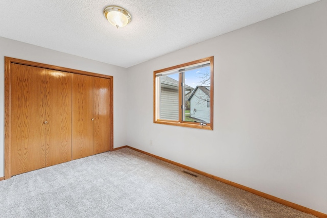 unfurnished bedroom with baseboards, carpet flooring, visible vents, and a closet