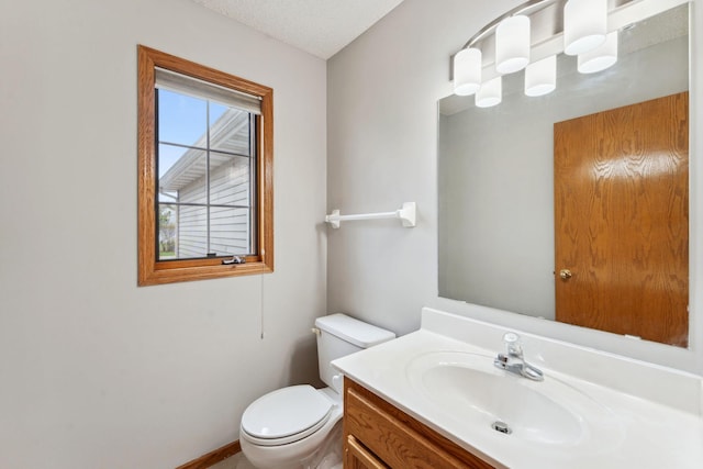 bathroom featuring toilet, baseboards, and vanity