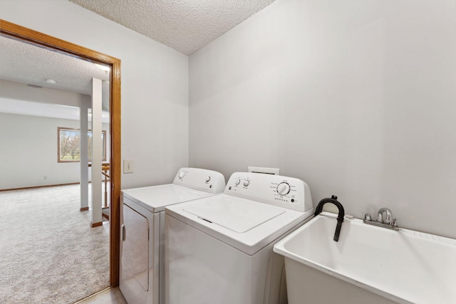 clothes washing area with carpet, laundry area, a textured ceiling, and washer and clothes dryer