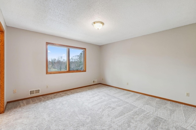 carpeted empty room with baseboards, a textured ceiling, and visible vents