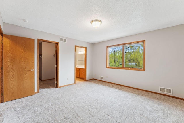 unfurnished bedroom with visible vents, a textured ceiling, baseboards, and light colored carpet