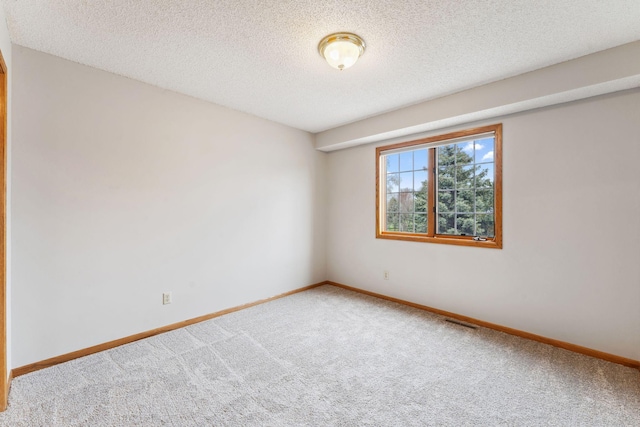 carpeted spare room with a textured ceiling, baseboards, and visible vents