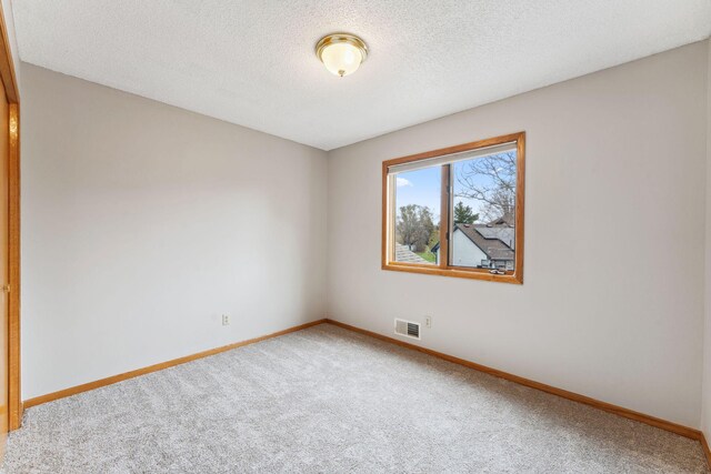 carpeted empty room with baseboards, a textured ceiling, and visible vents