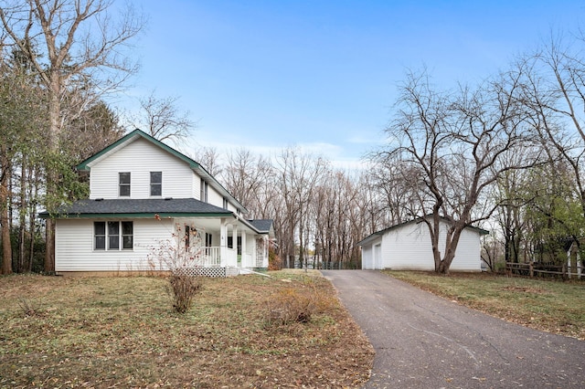 view of front of home featuring a garage, covered porch, an outdoor structure, and a front yard