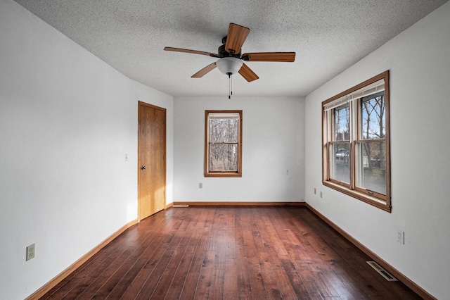 spare room featuring ceiling fan, dark wood-type flooring, and a textured ceiling