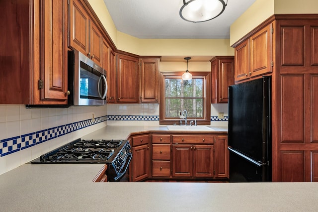 kitchen with hanging light fixtures, sink, backsplash, and black appliances