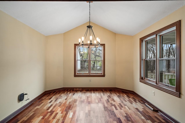 unfurnished dining area with vaulted ceiling, wood-type flooring, and a notable chandelier