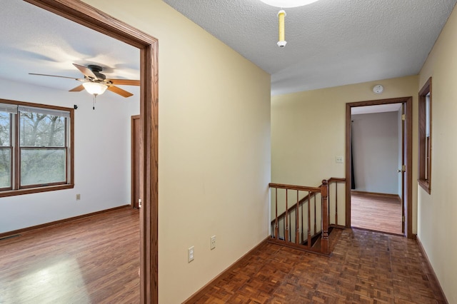 corridor with a textured ceiling and dark parquet floors