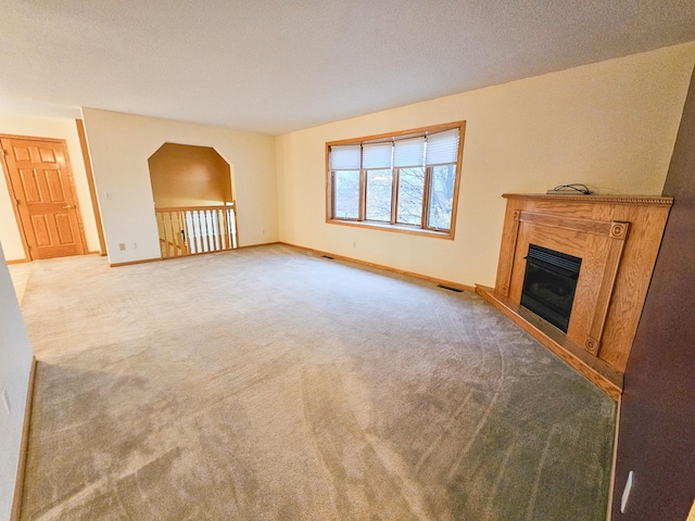 unfurnished living room featuring light colored carpet and a textured ceiling