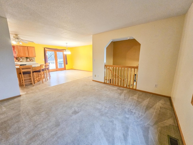 unfurnished living room with ceiling fan, light carpet, and a textured ceiling