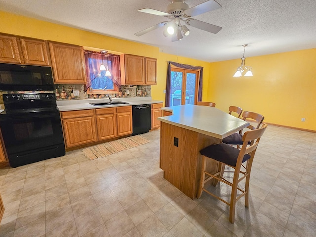 kitchen featuring a kitchen bar, sink, decorative light fixtures, a kitchen island, and black appliances