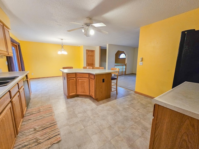 kitchen with a kitchen island, ceiling fan with notable chandelier, decorative light fixtures, dishwasher, and a breakfast bar area