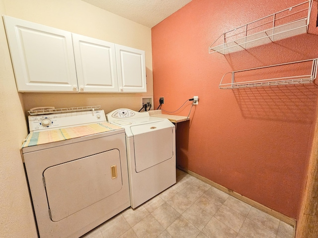 laundry area featuring independent washer and dryer, cabinets, and a textured ceiling