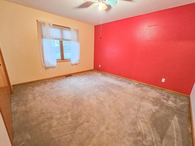 empty room featuring ceiling fan, carpet, and a textured ceiling