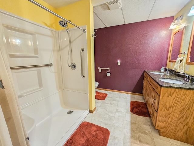 bathroom featuring toilet, a drop ceiling, vanity, and walk in shower