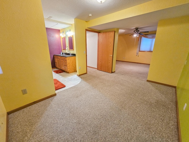 empty room with ceiling fan, light colored carpet, and a textured ceiling