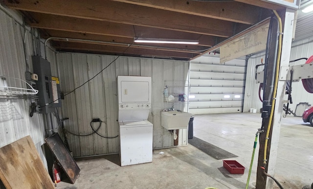 basement featuring stacked washer / drying machine and sink