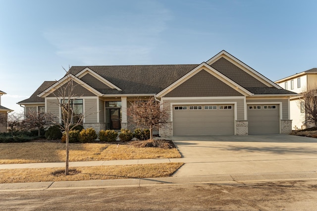 craftsman-style house with roof with shingles, stone siding, a garage, and concrete driveway