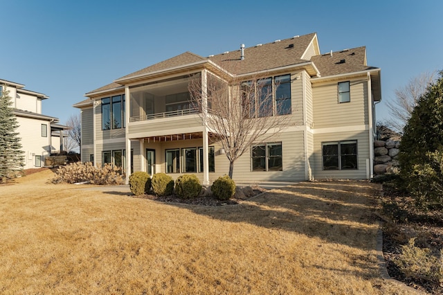 back of property featuring a lawn and a shingled roof
