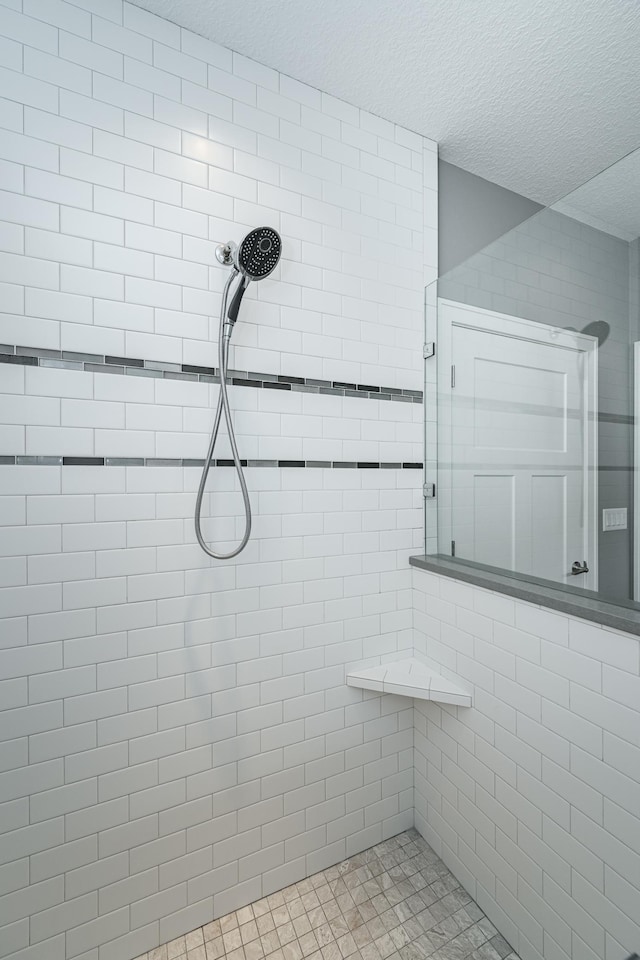 bathroom featuring a textured ceiling and tiled shower
