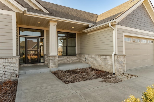 doorway to property with a shingled roof, covered porch, and a garage