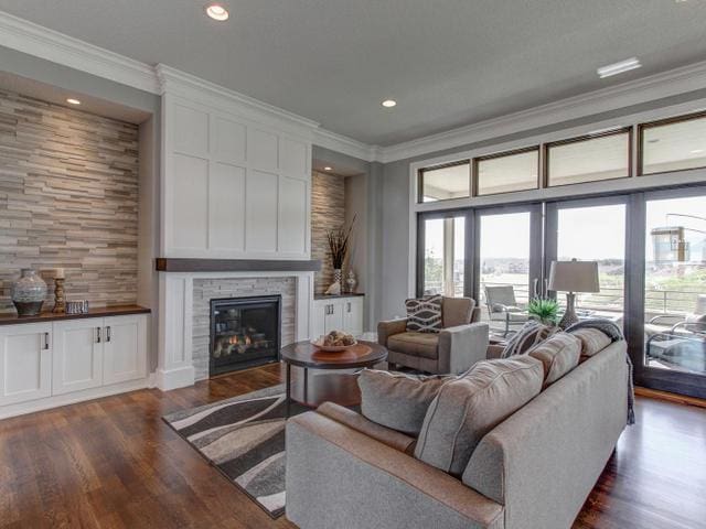 living room with dark wood-style flooring, crown molding, a fireplace, and recessed lighting